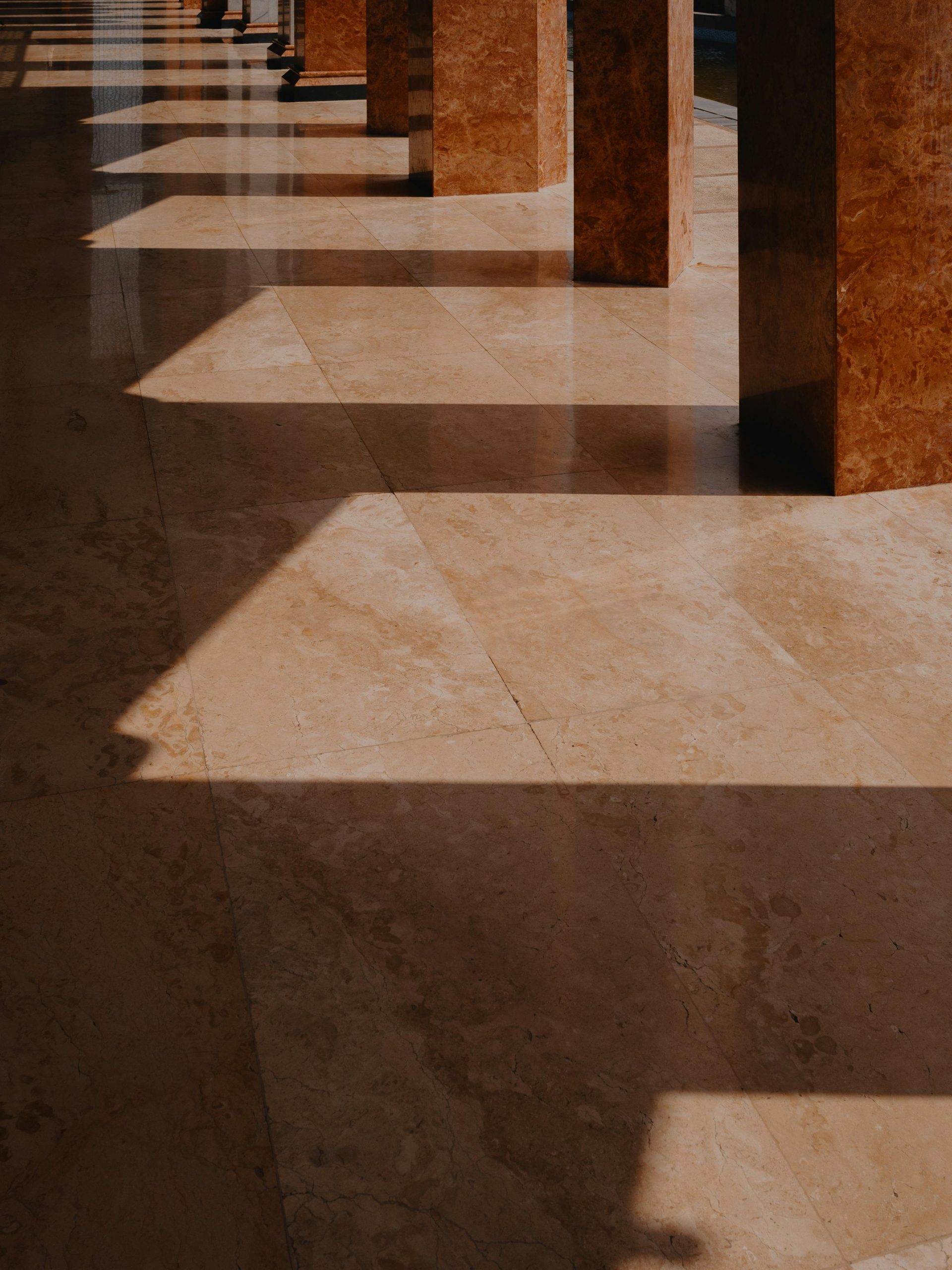 Captivating shadows cast by columns on marble floors in an Indonesian mosque during golden hour.