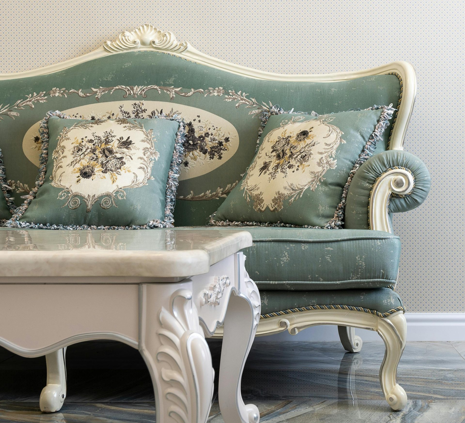 Living room interior with white table against cushions with floral ornament on couch in light house